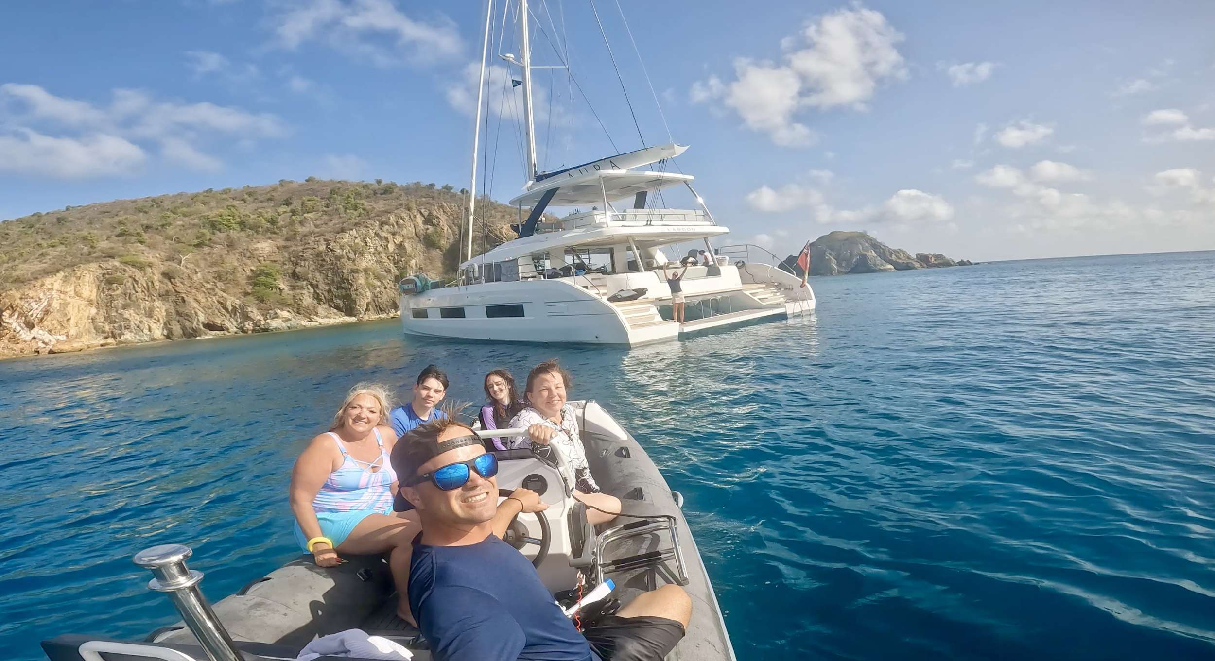 Aura Catamaran guests in the dinghy taling a selfie with the yacht in the background