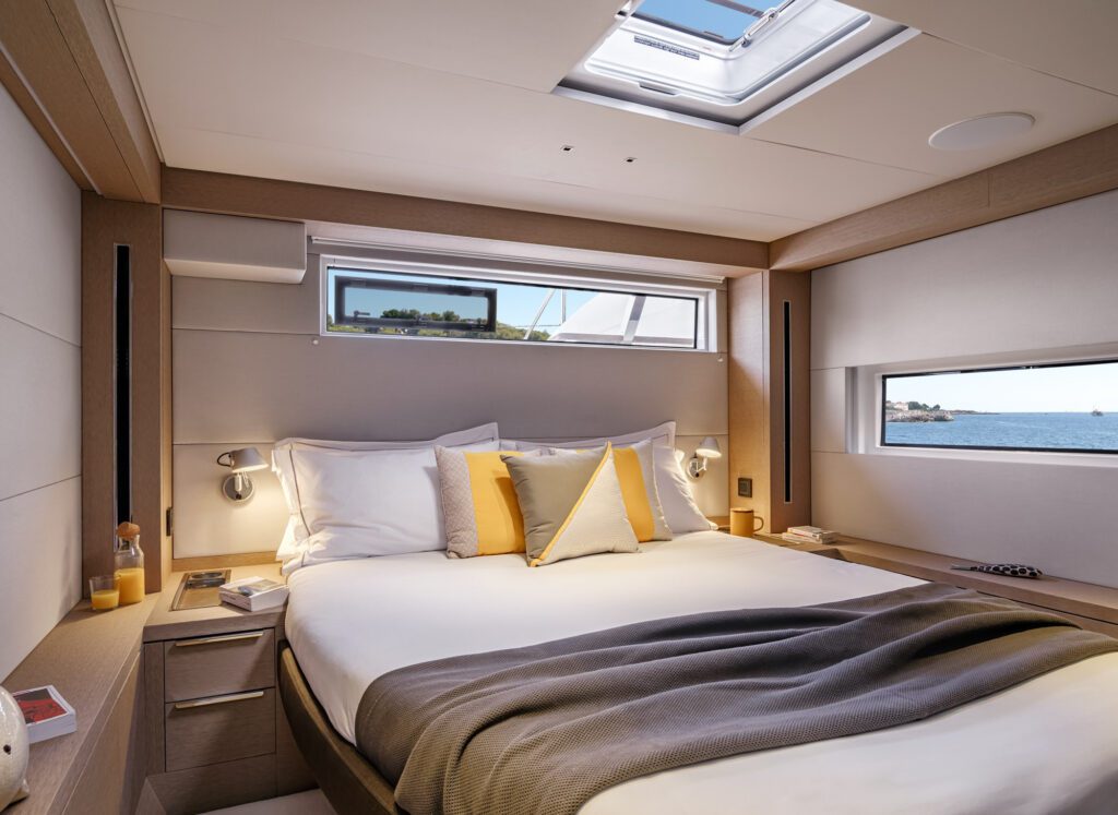 Seahome II ensuite bed with light colors, warm pillows and light entering the room